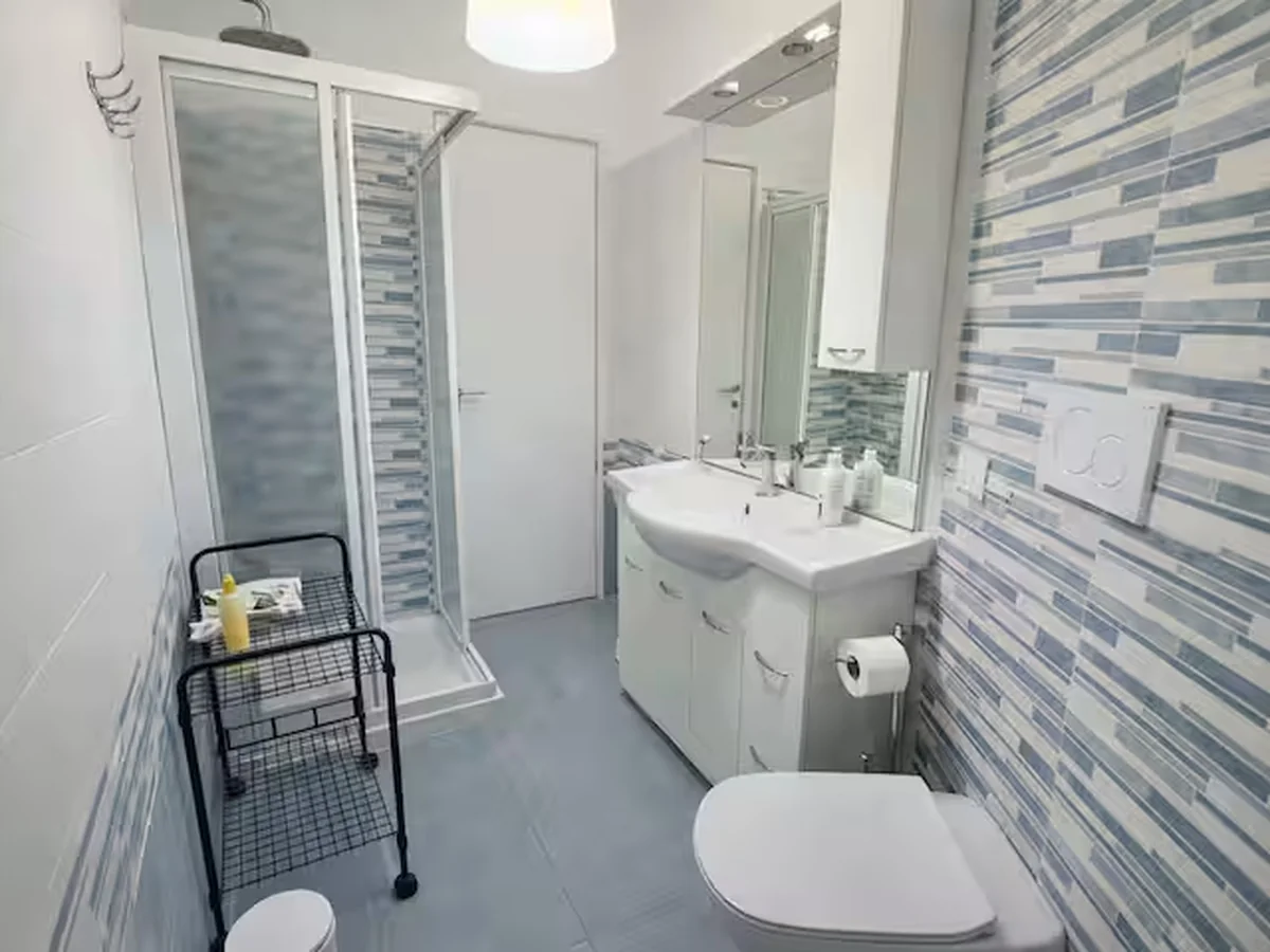 Modern bathroom with shower, vanity and blue vertical tile detail.