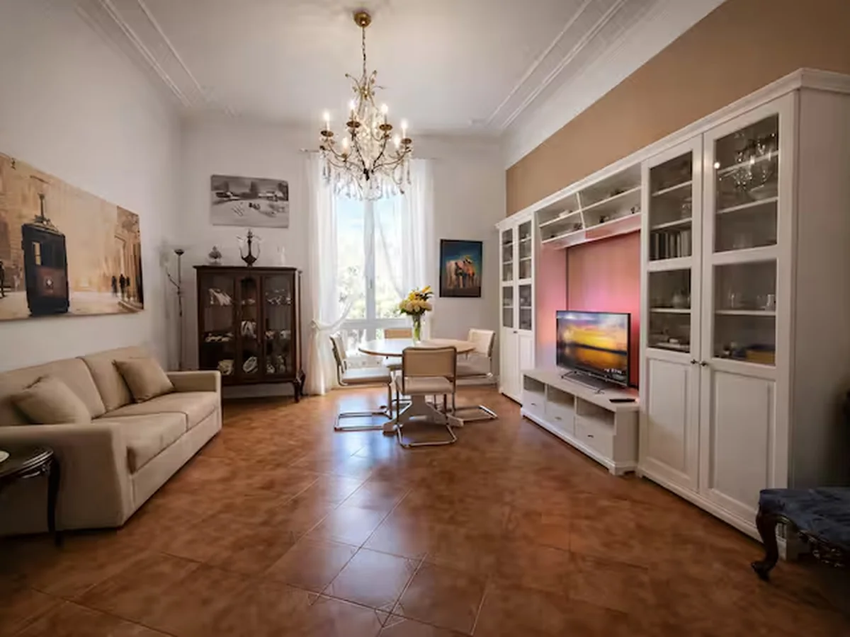 Elegant living room with chandelier, dining table and wall unit.