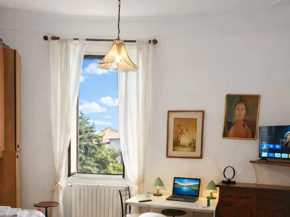View from inside the apartment toward the tall window and Milan sky.